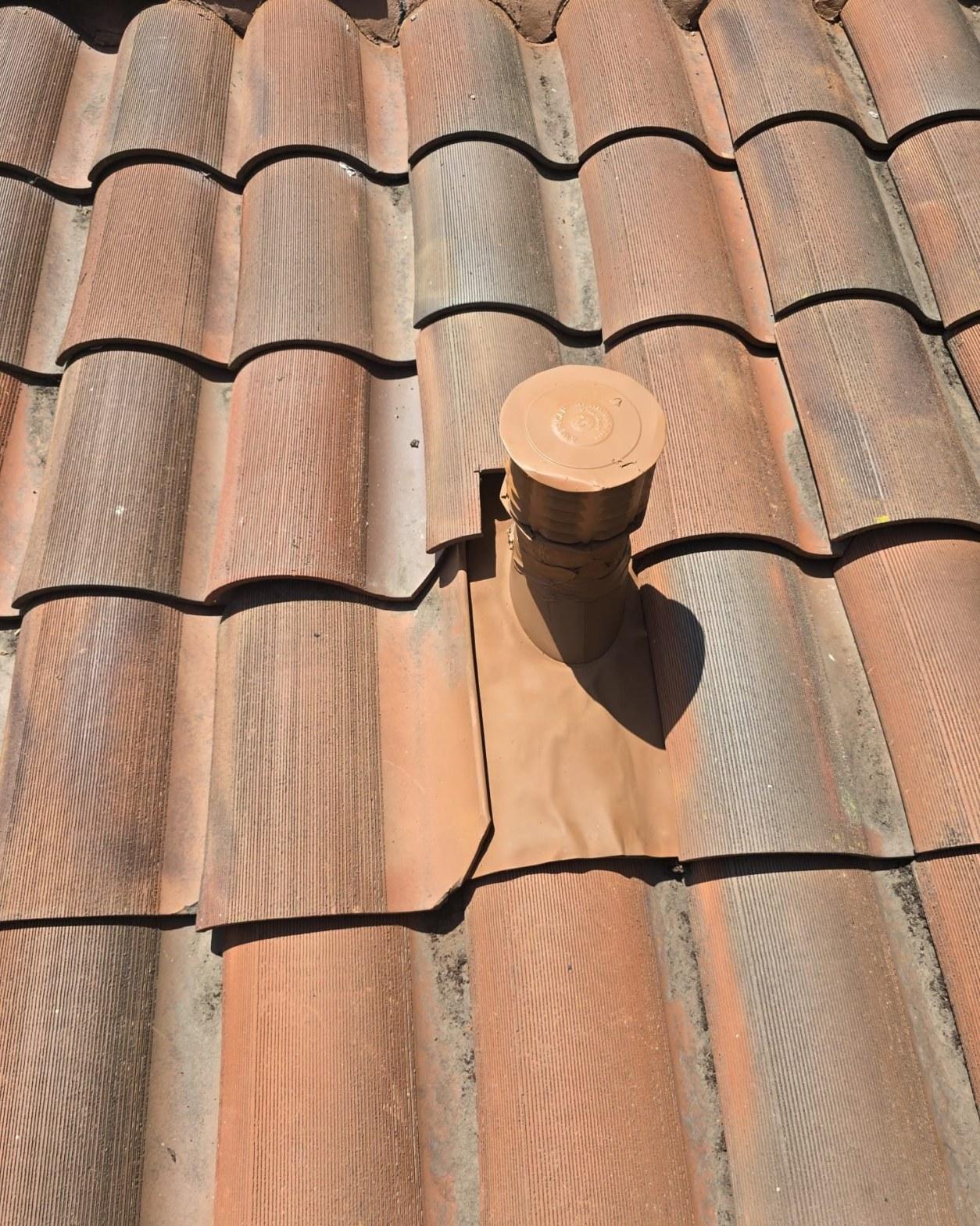 tile-roof-repair-vent-flashing-san-gabriel-3435 Brown plumbing vent stack with cap and lead flashing penetrating clay S-tile roof in sunlight.