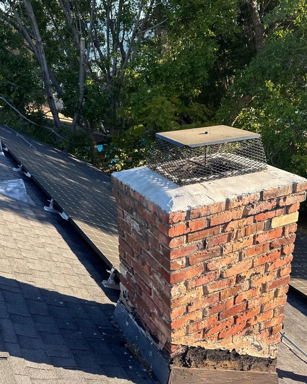 Aging brick chimney on a Sherman Oaks residential roof with separated base flashing and a metal chimney cap, adjacent to a solar array